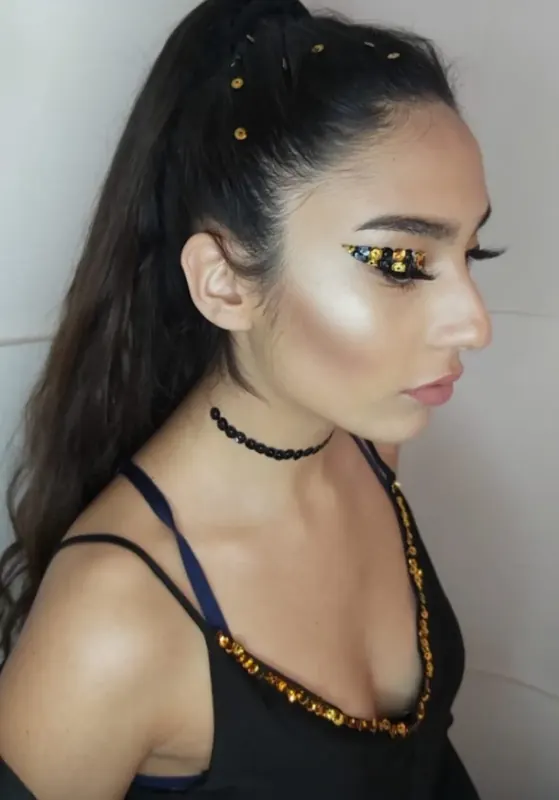 Perfil con delineado de glitter dorado, iluminador y coleta con brillos